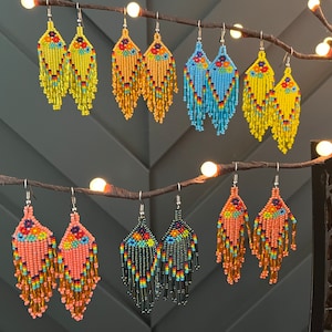 Pu&ograve; includere: Un set di 10 paia di orecchini pendenti con perline di vari colori, tra cui giallo, blu, arancione e verde. Gli orecchini sono realizzati con piccole perline colorate e hanno un design a frangia.