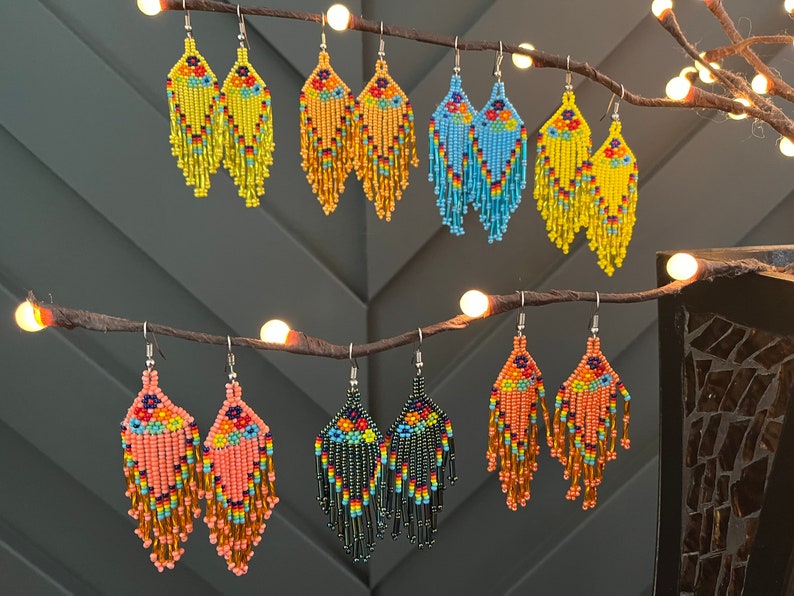 Pu&ograve; includere: Un set di 10 paia di orecchini pendenti con perline di vari colori, tra cui giallo, blu, arancione e verde. Gli orecchini sono realizzati con piccole perline colorate e hanno un design a frangia.