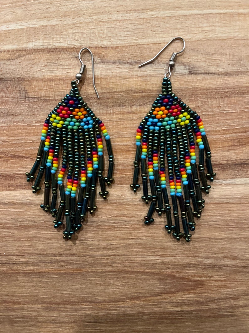 Pu&ograve; includere: Un paio di orecchini pendenti con un design di perline nere, verdi, blu, rosse, gialle e arancioni. Gli orecchini hanno ganci d'argento.