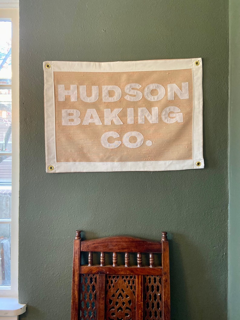 May include: A tan canvas banner with white text that reads "HUDSON BAKING CO."
