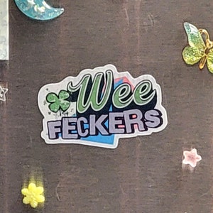 May include: A white sticker with a green shamrock and the text "Wee Feckers" in a colorful, stylized font.