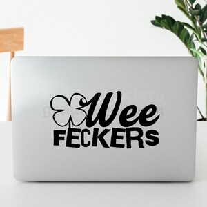 May include: A white laptop with a black shamrock and the text "Wee Feckers" on the lid.