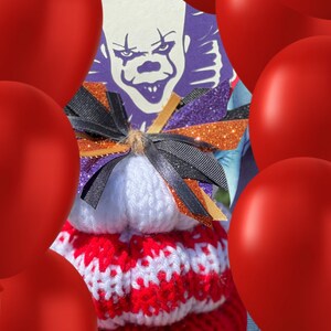 Op de afbeelding: Een rood-witte gebreide muts met een zwarte strik en een paars-oranje glitterachtergrond. De muts is omringd door rode ballonnen. De achtergrond is een paars-witte afbeelding van een clown met een enge uitdrukking.