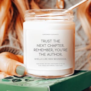 以下が含まれることがあります： 黒いラベルが付いた白いキャンドルジャー。ラベルには「Trust the next chapter. Remember, you're the author. Smells like new beginnings. 100% natural soy wax | Hand poured in the USA 9 oz | Vegan | Eco-friendly | Non-toxic」と書いてあります。