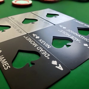 May include: A set of rectangular metal bottle openers shaped like playing cards, featuring a die-cut spade symbol in the centre. Each opener is engraved with an ace of spades icon, a unique name, and a nickname, including James, Kevin, and Johnathon.