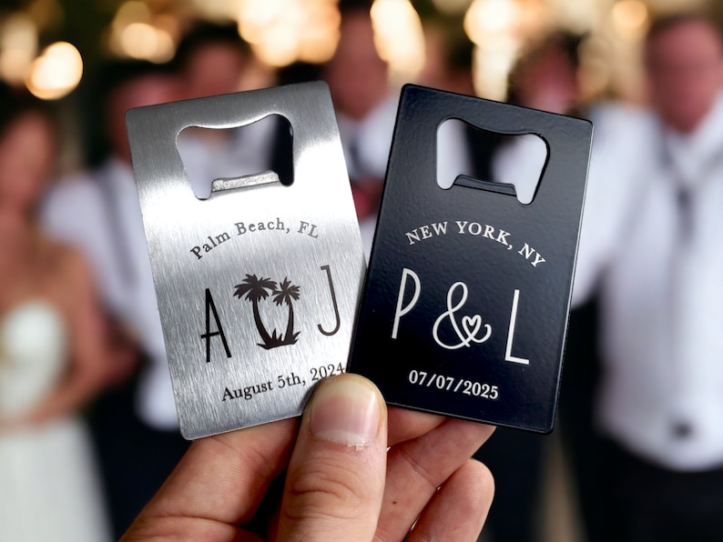 May include: Two rectangular bottle openers, one silver and one black, are held up. The silver opener says "Palm Beach, FL" with "A & J" and a palm tree design. The black opener says "New York, NY" with "P & L" and a heart symbol.