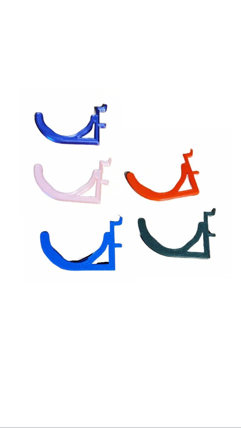 May include: Four 3D printed wall hooks in different colors: blue, pink, orange, and green. Each hook has a curved shape and a triangular base.