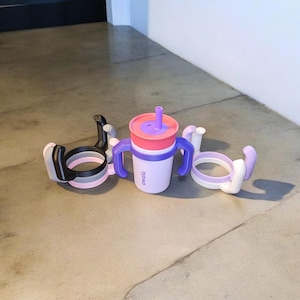 May include: Three different colored silicone cup holders with a purple and pink cup with a straw and the word "oxo" on the side.