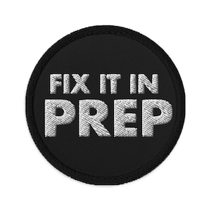 May include: Black round patch with white embroidered text that reads "Fix it in Prep".