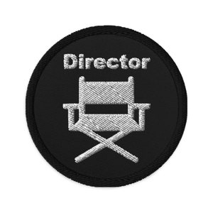 May include: Embroidered black patch with a white director's chair and the word "Director" in white text. The patch is circular with a black border and white stitching.