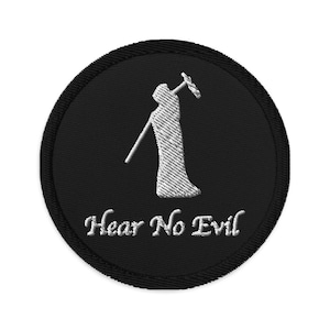 Puede incluir: Un parche bordado negro con una silueta blanca de una persona cubriéndose las orejas con las manos. El texto "Hear No Evil" está bordado en blanco debajo de la figura.