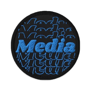 May include: Circular black embroidered patch featuring the word "Media" in blue, with a repeating pattern of the same word. The patch has a black border.
