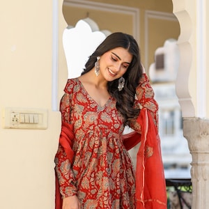 Puede incluir: Vestido rojo con estampado floral, mangas largas y cuello en V. El vestido se combina con una bufanda roja a juego. El vestido tiene una silueta fluida y un detallado estampado floral en tonos rojos, azules y beige.