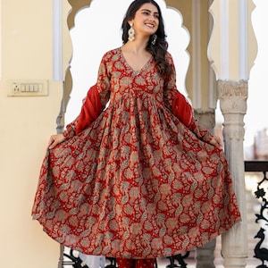 Puede incluir: Un vestido rojo con estampado floral, mangas largas y cuello en V. El vestido se combina con un pantal&oacute;n rojo a juego. Las mangas son de color rojo liso y el vestido tiene una silueta fluida. El conjunto es adecuado para diversas ocasiones.