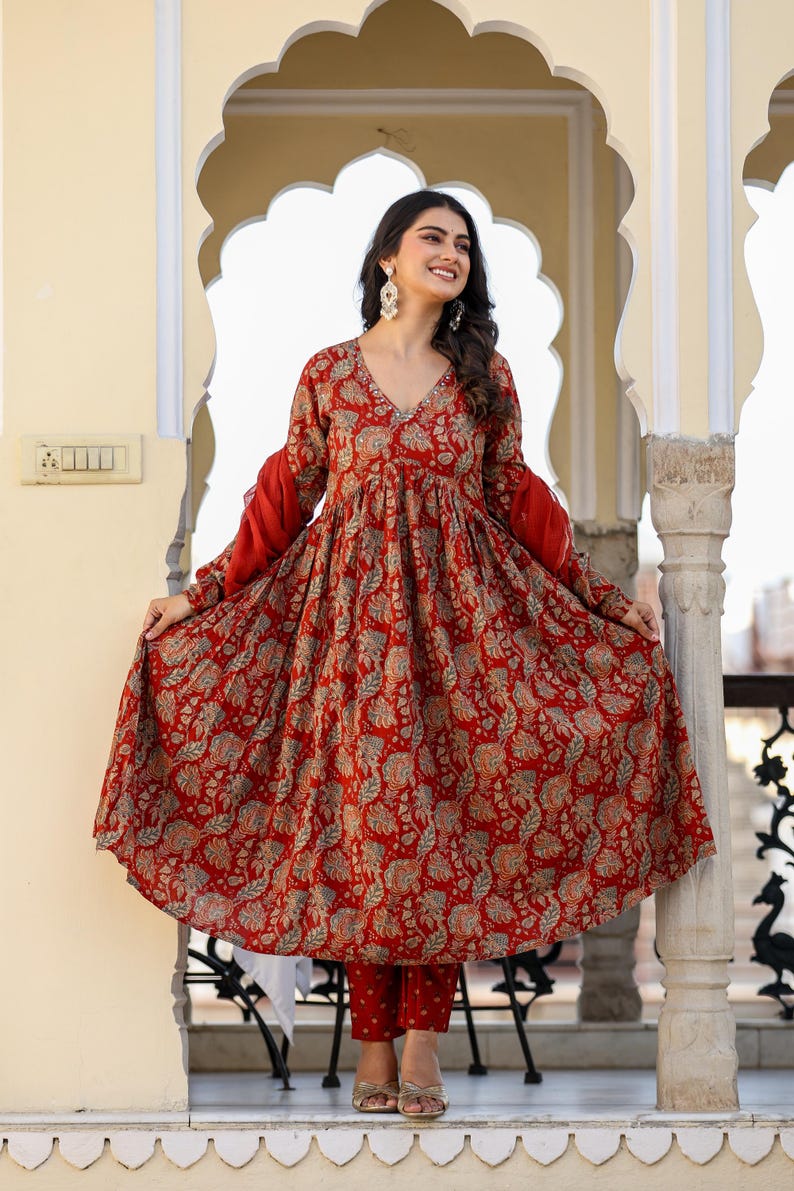 Puede incluir: Un vestido rojo con estampado floral, mangas largas y cuello en V. El vestido se combina con un pantal&oacute;n rojo a juego. Las mangas son de color rojo liso y el vestido tiene una silueta fluida. El conjunto es adecuado para diversas ocasiones.
