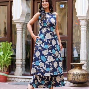 May include: A sleeveless navy blue floral print dress and matching pants. The dress features a white and light blue floral pattern. The outfit is worn with gold-colored heels. The outfit is suitable for casual or semi-formal occasions.