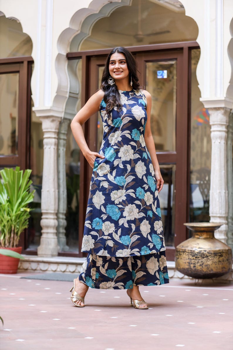 May include: A sleeveless navy blue floral print dress and matching pants. The dress features a white and light blue floral pattern. The outfit is worn with gold-colored heels. The outfit is suitable for casual or semi-formal occasions.