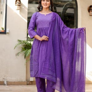 May include: A striking purple salwar kameez outfit. The set comprises a long-sleeved tunic with detailed embroidery, coordinated straight-leg trousers, and a flowing dupatta. The outfit is crafted from a lightweight material, ideal for warmer climates. The design features a delicate pattern.
