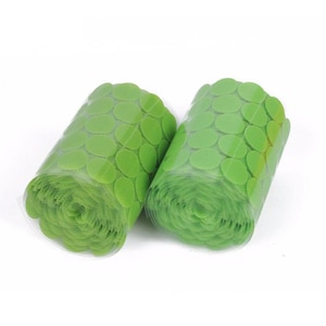 May include: Two rolls of green adhesive dots on a white background. The dots are arranged in a circular pattern on a clear backing.