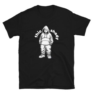 以下が含まれることがあります： 白いフード付きのパーカーを着た人物のイラストと「thic shady」というテキストが書かれた黒いTシャツ。