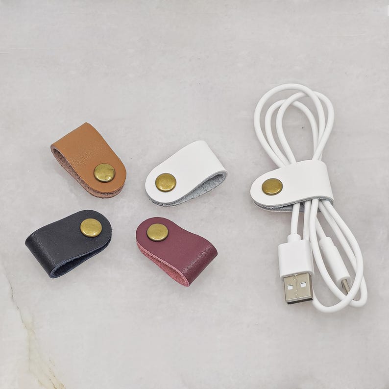 KALLACALLA leather cable organizer clips for chargers and earphones, shown in multiple colors with one in use.