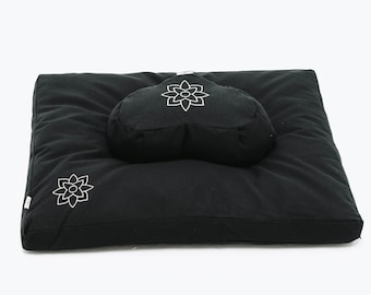 May include: Black meditation cushion set with a round cushion and a square cushion. Both cushions have white embroidered lotus flower designs.