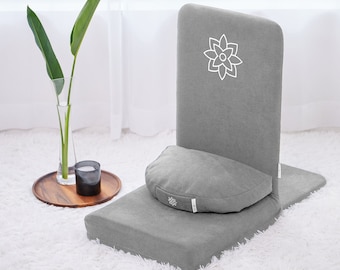May include: Gray meditation cushion with a back support and a removable cushion. The back support has a white embroidered flower design.