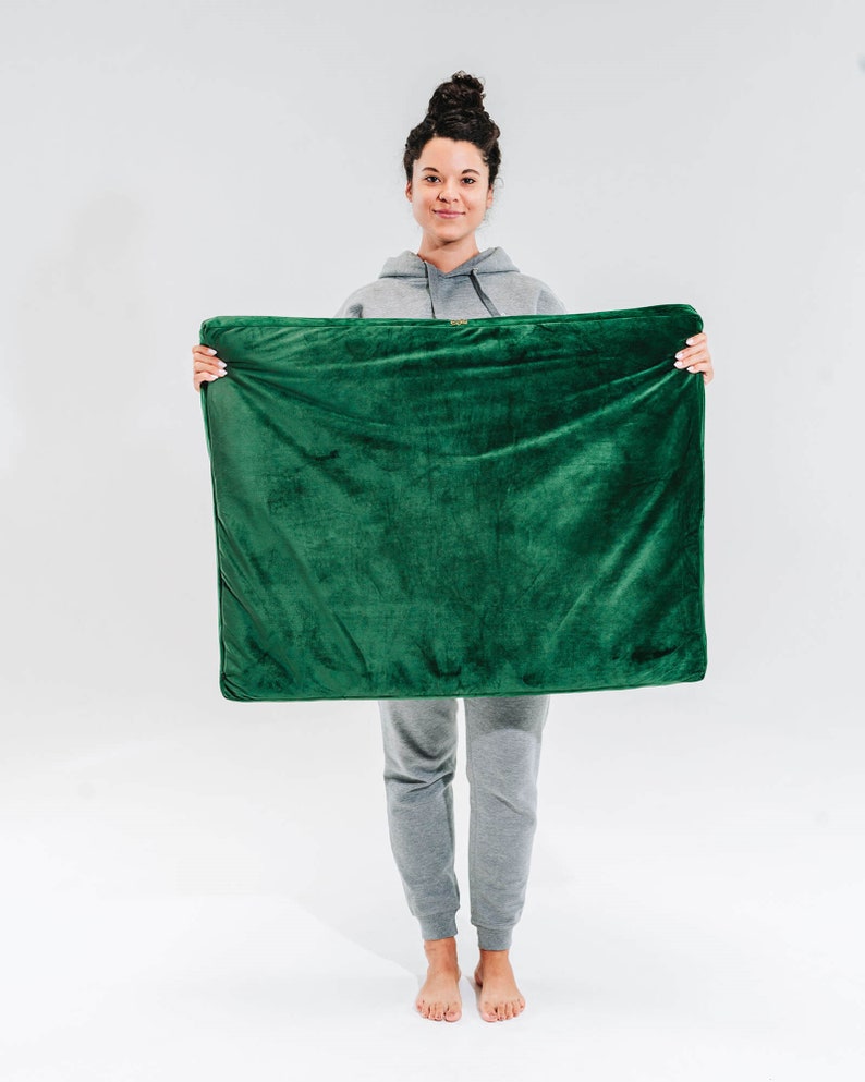 May include: A person is holding a green plush throw blanket in front of them. The blanket is soft and fluffy, and it would be perfect for cuddling up on the couch.