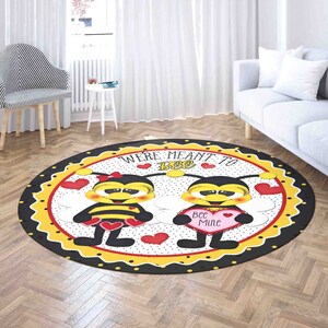 May include: A round rug with a black, yellow, and red design featuring two cartoon bees with the text "We're meant to bee" and "Bee Mine".