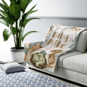 May include: A white baby blanket with a brown and green watercolour design of dragons and the text "Baby Mike".