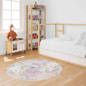 May include: A round pink and white rug with a floral design and a cartoon elephant wearing a pink tutu. The rug has the name "Olivia" written on it.