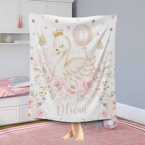 May include: A white and gold swan with a pink crown and a pink balloon is surrounded by pink and gold flowers. The text "Olivia" is written below the swan. The background is white with pink and gold polka dots.