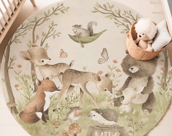 May include: A round play mat with a woodland theme. The mat features a brown bear, a fox, two deer, a squirrel, a hedgehog, a robin, and butterflies. The mat is beige with green foliage and has the name "Mike" written on a tree stump.