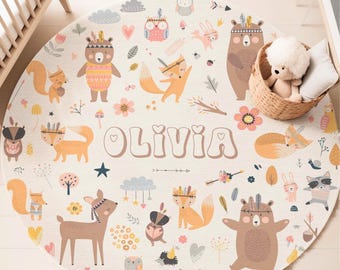 May include: A round, off-white rug featuring a woodland animal theme. The rug has illustrations of bears, foxes, deer, owls, and other forest creatures. The name "OLIVIA" is printed in the center. The rug is designed for a nursery or children's room.