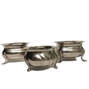 以下が含まれることがあります： 丸い脚が付いた銀製のボウルが3つ。ボウルは金属製で、光沢のある仕上げになっています。