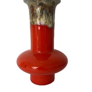 May include: A red ceramic vase with a brown and white glaze on the top. The vase has a rounded base and a narrow neck.