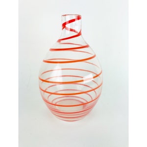 May include: A clear glass vase with a swirling pattern of red and orange stripes.