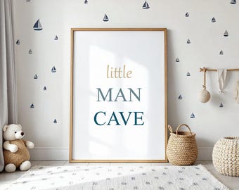 May include: A framed print with the words "little MAN CAVE" in gold and blue lettering. The room is decorated with sailboat wall decals, a woven basket, a white rug, and a teddy bear.