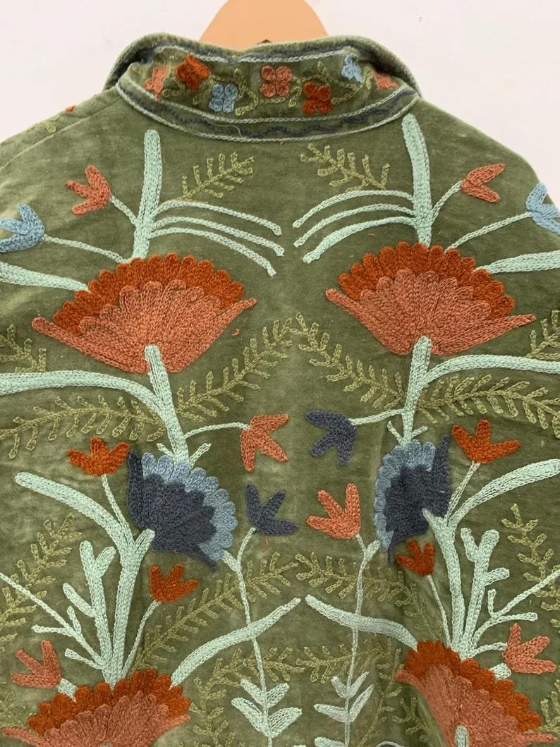 Pu&ograve; includere: Giacca verde oliva con ricami floreali intricati nei toni dell'arancione, blu e verde chiaro. La giacca presenta un colletto e cuciture dettagliate, mostrando un'estetica boh&eacute;mien.