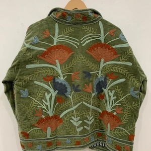 Pu&ograve; includere: Giacca verde oliva con ricami floreali dettagliati nei toni dell'arancione, blu e verde. La giacca presenta un collo e una vestibilit&agrave; rilassata. I ricami sono dettagliati e coprono la schiena della giacca, creando un'estetica boh&eacute;mien.