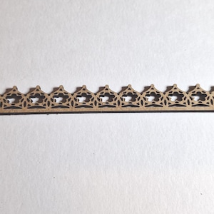May include: A thin, wooden decorative trim piece with a repeating pattern of openwork star and triangle shapes. The trim is a light brown color and appears to be made of laser-cut wood. The design is symmetrical and suitable for craft projects.