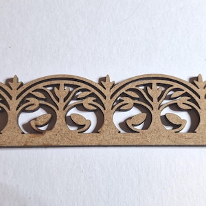 May include: A decorative wooden trim with a repeating pattern of arched designs, each featuring a stylized tree with leaves. The trim is a light brown color and has a delicate, openwork design, suitable for craft projects.