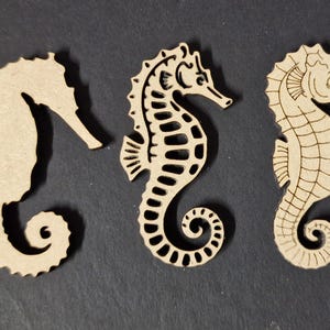 May include: Three light brown seahorse cutouts arranged in a row. The first is a solid silhouette, the second features a cutout skeletal pattern, and the third displays detailed etched line work showing the seahorse's anatomy and eye.