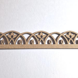 May include: A decorative wooden trim piece with a repeating floral and arched design. The trim is a light brown color and features cut-out details of flowers and oval shapes. The design is symmetrical and suitable for craft projects.