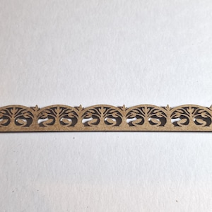 May include: A decorative wooden trim piece with a repeating tree and arch design. The trim is a light brown color and has a series of arched cutouts. The design is symmetrical and suitable for craft projects or home decor.