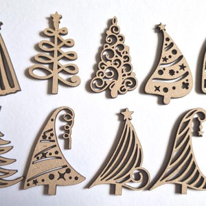 Pode incluir: Uma coleção de dez enfeites de árvore de Natal de madeira em vários designs. Os enfeites são cortados de madeira castanha clara e apresentam padrões intrincados, incluindo estrelas, redemoinhos e formas geométricas.
