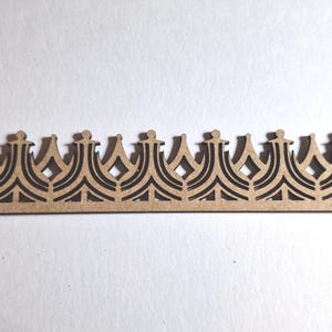 May include: A decorative wooden crown-shaped border with a repeating pattern. The border is made of light brown wood with a dark brown, intricate design. The design features a series of crown shapes with diamond and arch details. This item is suitable for craft projects.