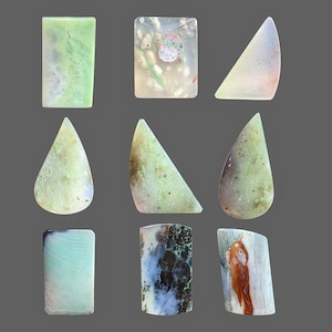 Op de afbeelding: Assortiment van 12 groene, witte en bruine agaat cabochons in verschillende vormen, waaronder rechthoeken, driehoeken en druppelvormen.