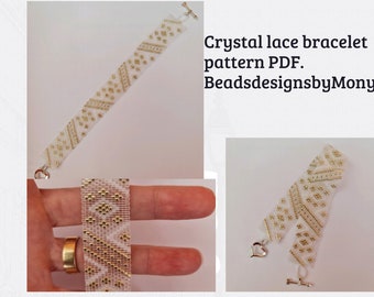 Peut inclure: Un bracelet en perles blanc et or avec un motif en dentelle de cristal. Le bracelet est doté d'un fermoir à bascule et d'un charm en forme de cœur. Le texte "Crystal lace bracelet pattern PDF. BeadesignsbyMony." est visible.
