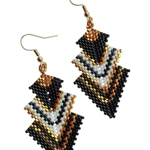 May include: Geometric beaded earrings in black, white, and gold. The earrings feature a layered, chevron-like design with gold-colored ear wires. The earrings are made of small, colorful beads, creating a textured surface.